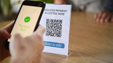 Customer paying with digital money scanning with a smartphone a qr code in a cafeteria.