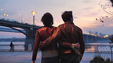 Beautiful young couple against the backdrop of a colorful sunset and city lights. Romantic atmosphere. Two lovers