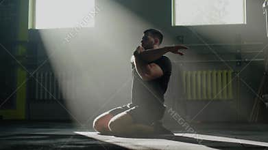 Muscular man has body stretching before workout.