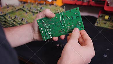 Hands inserting electronic component into printed circuit board - close up