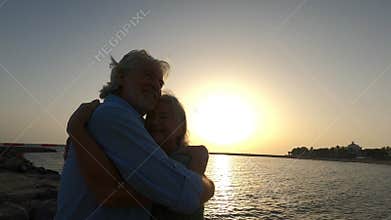 Close up and portrait of two happy and active seniors or pensioners having fun and enjoying looking at the sunset smiling with the