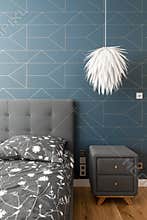 Bed with patterned bedding, white lamp grey nightstand