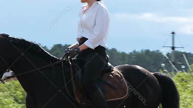 Girl in a white shirt and black pants rides a horse