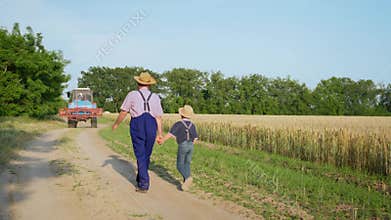 Agribusiness, elderly male farmer walks hand in hand with his grandson