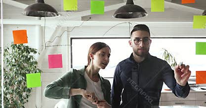 Skilled young arabian male manager drawing charts on glass wall.