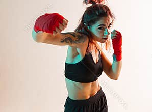 A female boxer with bandages on his hands works out an upper hand and elbow strike.