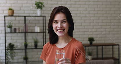 Woman smiling looking at camera holding glass of still water
