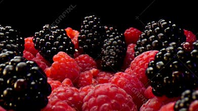 Blackberries and raspberries on a black background. Composition of a raw and fresh forest fruits close up in 4K.