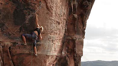 Young woman climbing an extreme difficult rock