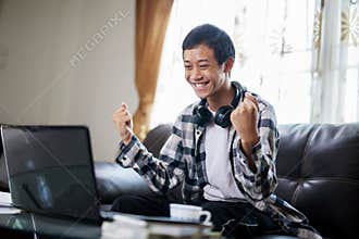 Asian student exciting in fron of laptop