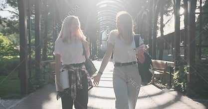 Two happy smiling talking girls teenagers students walking together