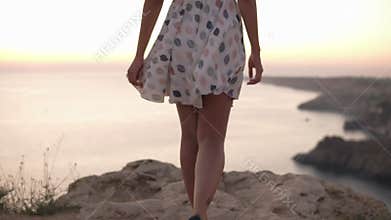 Close back view of slender woman tender walk in slow motion. Blonde woman walking by the cliff very carefully. Wearing