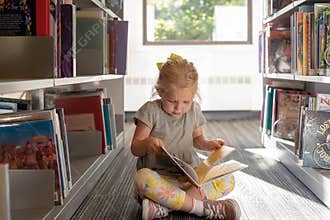 Barrington, IL/USA - 09-23-2019: Little girl reading a book at the library