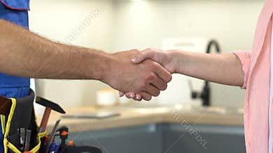 Repairman with tools on belt and lady customer shaking hands, service quality