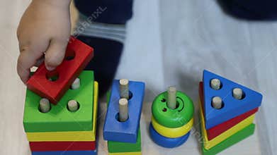 One year old child boy plays with geometric sorter wooden constructor, close-up of child`s hand and toy, 50 fps, slow motion