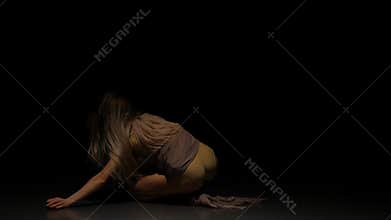 Appealing female dancing in dark studio at spotlight. Slow motion