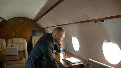 Businessman talk by phone indoor of private jet cabin