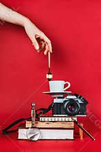 Balancing still life composition with books, vintage camera, cup of coffee and spoon