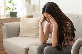 Asian woman are holding their hands to the head in pain on the sofa at home, Young women have severe headaches from migraines,