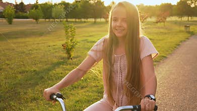 Girl ride bicycle on park alley - close up