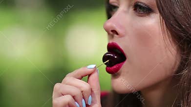 Pretty woman seductively eating cherry