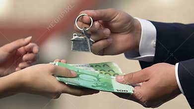 Real estate agent receiving euro and giving house key female buyer, agreement