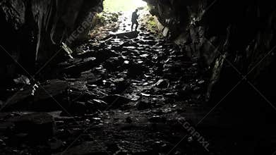 Traveler descends into cave. Stock footage. Traveler explores cave tunnel going down rope. Dangerous cave tunnels