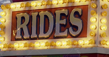 Rides sign at night at carnival fair grounds.