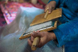 Woman with brushes preparing a wool for spining a woolen string for berber moroccan carpets