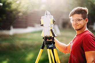 handsome surveyor working with total station with coordinates, cartography industry details