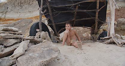 Caveman, manly boy. Funny young primitive boy outdoors. Evolution survival concept. Calm boy outside sitting at his