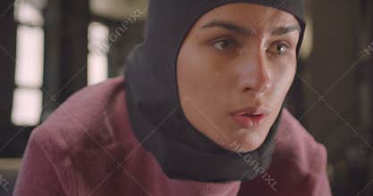 Closeup portrait of young motivated athletic muslim female in hijab working out in gym indoors
