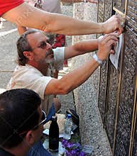 At the EAA Memorial Wall a Man Rubs a Deceased Loved Ones Name on Paper