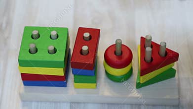 Baby puts a circle on the pin in a wooden constructor, slow motion. One year old child`s hand and the toy, close up