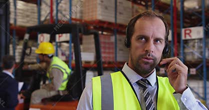 Male warehouse manager using headset and tablet 4k