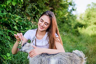 Woman and small goat green grass. Farm and farming concept. Village animals. Girl play cute goat. Feeding animal