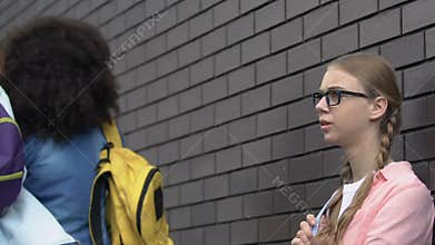 Cruel teenage girls insulting or threatening nerd, emotional bullying, abuse