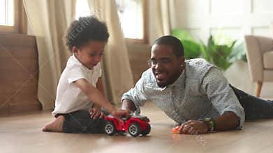 African father and little son playing with toy cars indoors