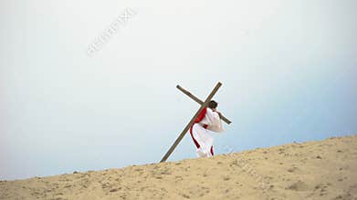 Jesus with heavy wooden cross hardly walking, biblical story of crucifixion