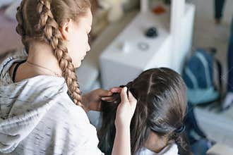 Friend making pigtail hair of teen girl