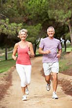 Senior couple running in park