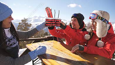 Smiling friends spending time together and drink after skiing in cafe at ski resort in mountains