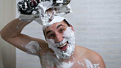 A strange man shaves his hair on his head using shaving foam and hockey skates, removing hair with a blade from his