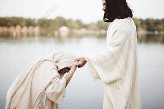 Shallow focus shot of a female grabbing the hand of Jesus Christ for healing and help
