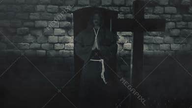 Catholic blind monk holding hand in prayer in front of a grave