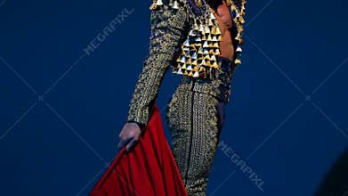 Torero in blue and gold suit or typical Spanish bullfighter isolated spotlight on a blue background. Close up, slow