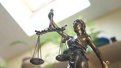 Statue of Themis or Lady Justice on Bookshelf Background