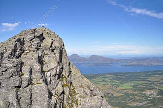 Grey granite cliffs of Seven Sister mountains, Norway with Donna island and blue Norwegian sea in background