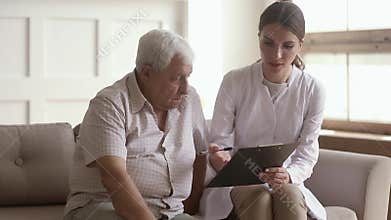 Young woman nurse caregiver holding clipboard consulting old elder man