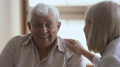 Elder man talking to mature doctor caregiver telling complaints laughing